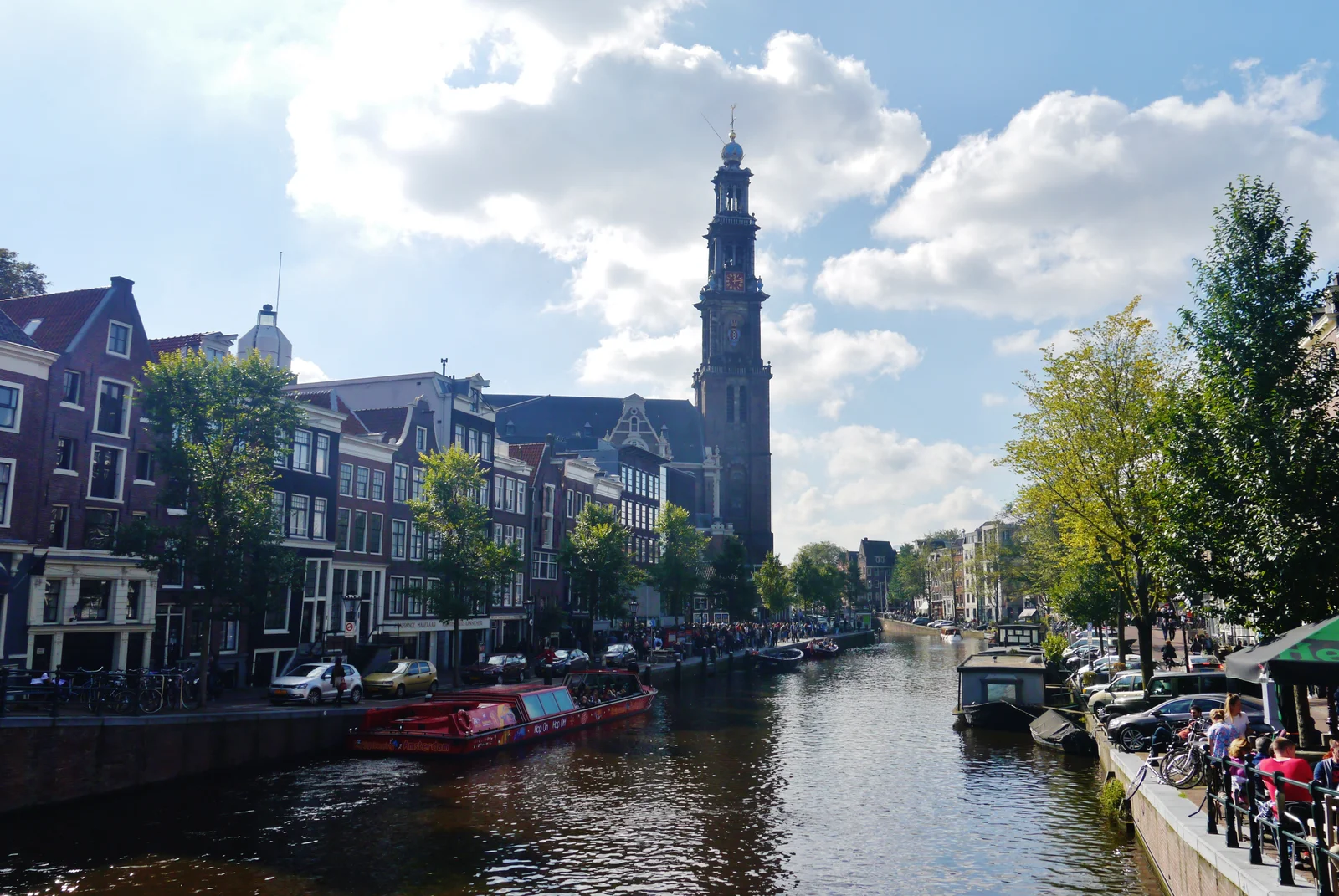 Westerkerk tower and canal cruise boats boarding along the Prinsengracht near the Anne Frank House in Amsterdam